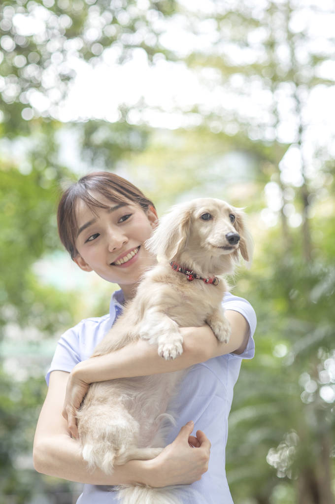 年轻的亚洲妇女与狗在街上